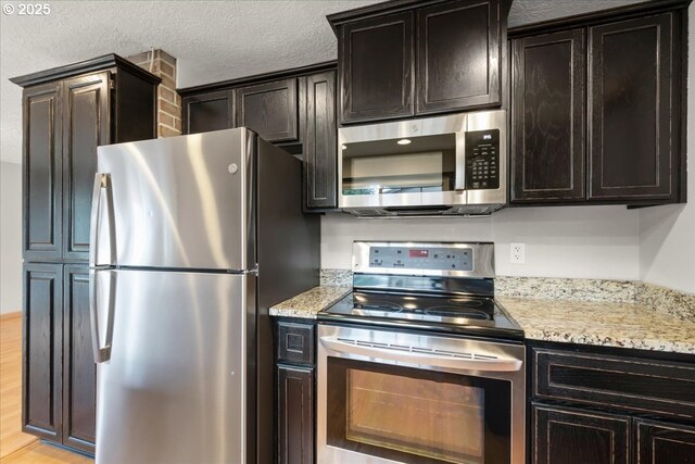 4603 SE 16th Ct, Gresham, OR 97080 - kitchen with stainless steel appliances, light stone counters, light wood finished floors, and a textured ceiling