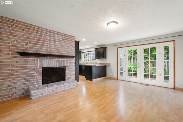 4603 SE 16th Ct, Gresham, OR 97080 - unfurnished living room with light wood finished floors, a textured ceiling, a fireplace, recessed lighting, and french doors