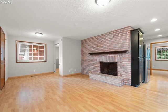 4603 SE 16th Ct, Gresham, OR 97080 - unfurnished living room featuring light wood finished floors, a brick fireplace, a textured ceiling, and recessed lighting