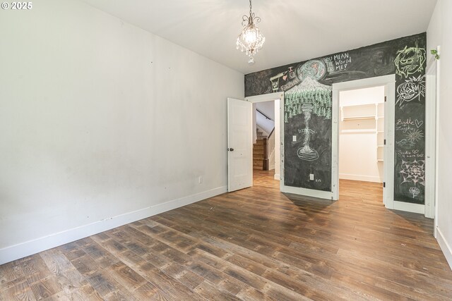 39665 SE Rude Rd, Sandy, OR 97055 - unfurnished bedroom with baseboards, wood finished floors, a chandelier, a walk in closet, and an accent wall