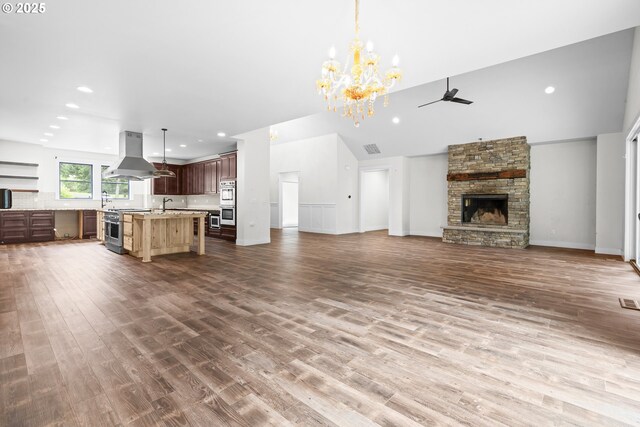 39665 SE Rude Rd, Sandy, OR 97055 - unfurnished living room with a ceiling fan, a stone fireplace, wood finished floors, a chandelier, and recessed lighting