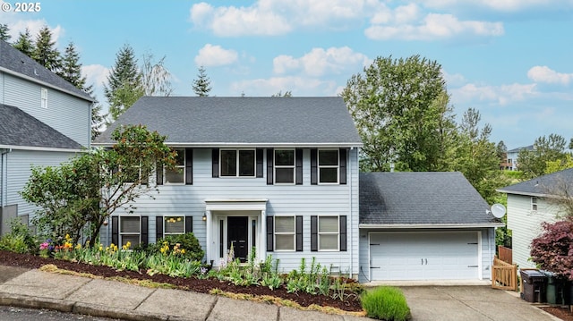 colonial house with a garage, concrete driveway, and a shingled roof