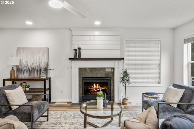 living room featuring wood finished floors, a fireplace, recessed lighting, a textured ceiling, and baseboards