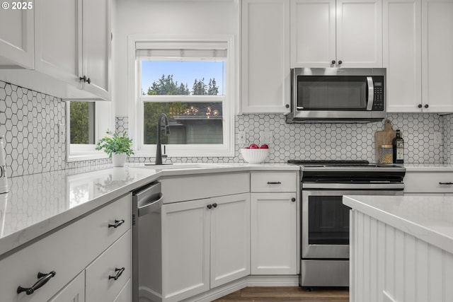 kitchen featuring appliances with stainless steel finishes, a sink, backsplash, and white cabinets