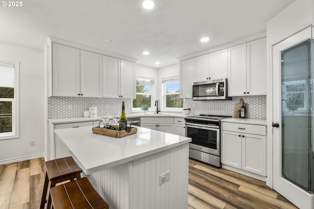 kitchen with stainless steel appliances, a kitchen breakfast bar, light wood-style flooring, light countertops, and recessed lighting