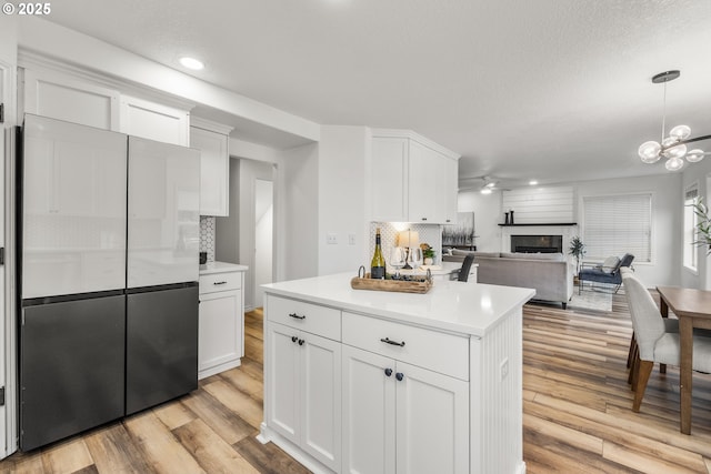 kitchen featuring a fireplace, decorative backsplash, white cabinets, light wood finished floors, and recessed lighting