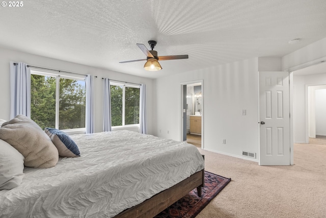bedroom featuring light colored carpet, a ceiling fan, baseboards, connected bathroom, and a textured ceiling