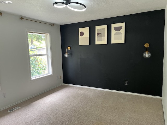 carpeted empty room with a textured ceiling and baseboards