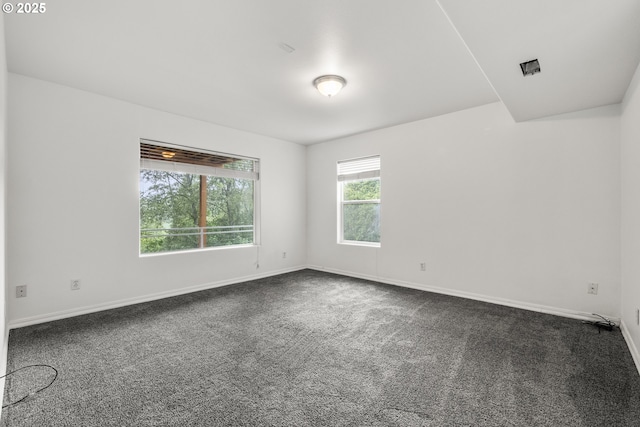 empty room with dark carpet and baseboards