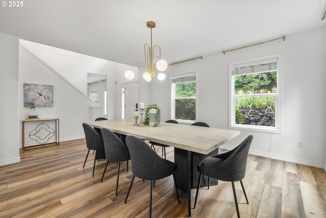 dining room with light wood-style flooring, baseboards, and a chandelier
