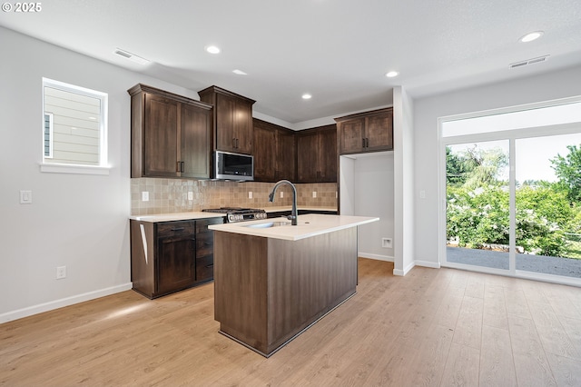 195 SE Acacia Dr, Gresham, OR 97080 - kitchen featuring stainless steel microwave, decorative backsplash, light wood finished floors, light countertops, and recessed lighting