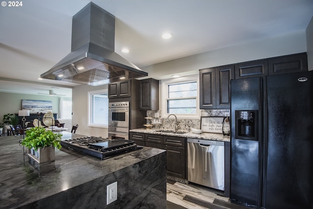 kitchen with dark brown cabinetry, island range hood, stainless steel appliances, a sink, and decorative backsplash