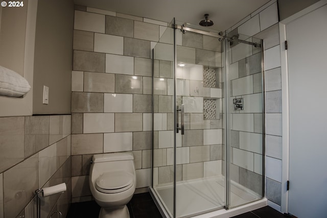 full bath featuring a stall shower, tile walls, and toilet