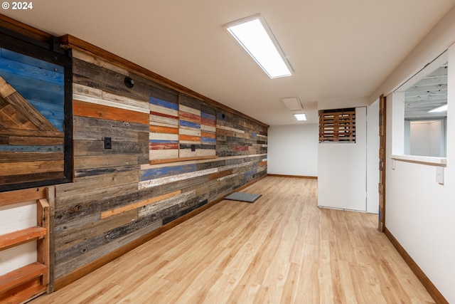 interior space featuring light wood-style floors, wood walls, and baseboards