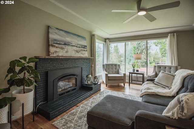 interior space featuring a ceiling fan, a glass covered fireplace, plenty of natural light, and wood finished floors