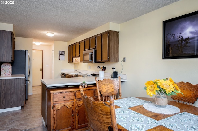 kitchen featuring kitchen peninsula, appliances with stainless steel finishes, and a textured ceiling