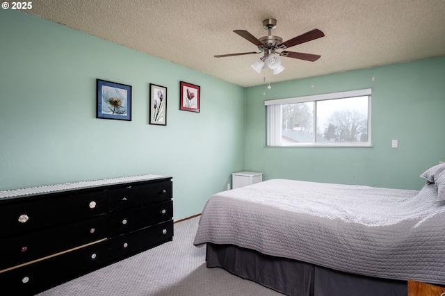 carpeted bedroom featuring ceiling fan and a textured ceiling