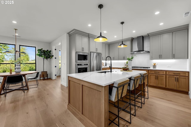 3800 W 2nd St, Washougal, WA 98671 - kitchen with wall chimney exhaust hood, stainless steel appliances, decorative backsplash, a kitchen breakfast bar, and light wood-type flooring