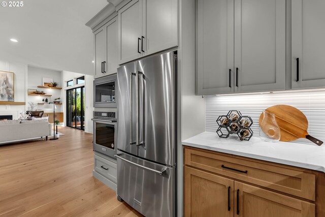 3800 W 2nd St, Washougal, WA 98671 - kitchen with appliances with stainless steel finishes, light wood finished floors, backsplash, recessed lighting, and a lit fireplace