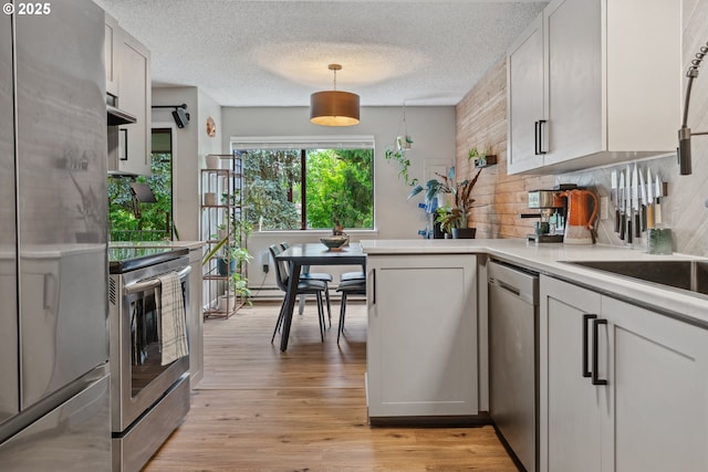6745 SW Scholls Ferry Rd Unit 10, Beaverton, OR 97008 - kitchen featuring appliances with stainless steel finishes, tasteful backsplash, light countertops, light wood-style floors, and a peninsula