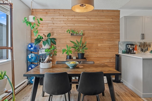 6745 SW Scholls Ferry Rd Unit 10, Beaverton, OR 97008 - dining room featuring a baseboard radiator, wooden walls, light wood-type flooring, plenty of natural light, and baseboards