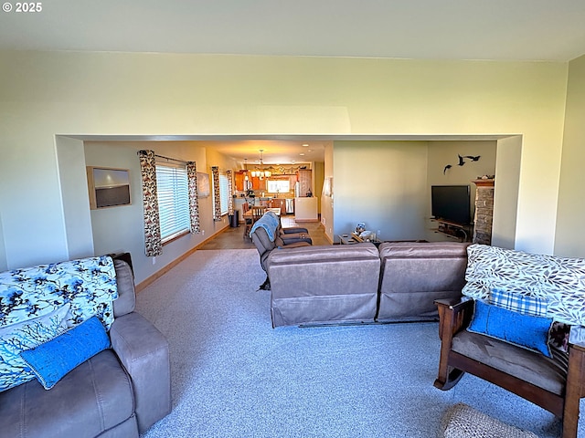 carpeted living area with baseboards and a notable chandelier