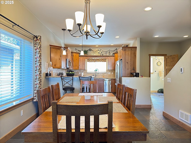 dining area featuring stone tile floors, visible vents, an inviting chandelier, and baseboards