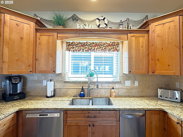 kitchen with stainless steel dishwasher, brown cabinetry, backsplash, and a sink