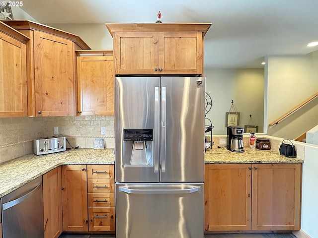 kitchen with tasteful backsplash, a peninsula, stainless steel appliances, and light stone countertops