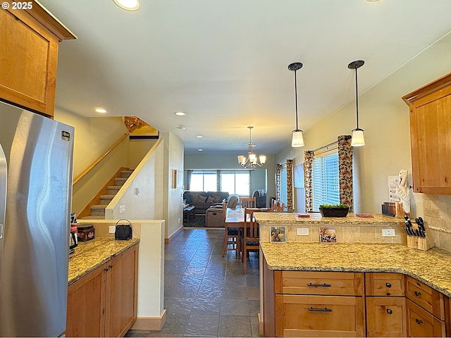 kitchen with a chandelier, brown cabinets, a peninsula, and freestanding refrigerator