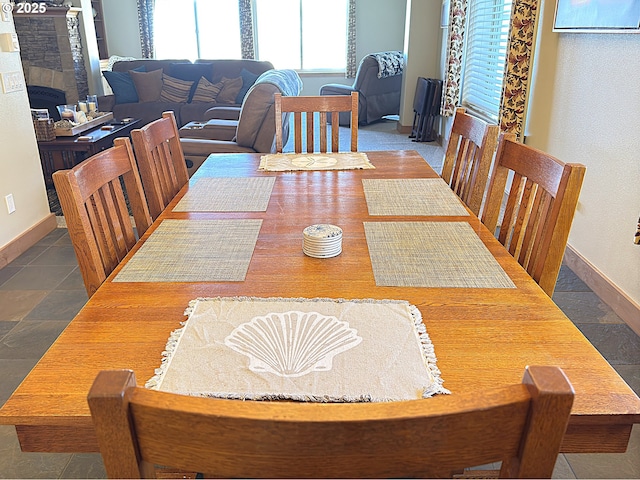 dining space featuring a tiled fireplace and baseboards