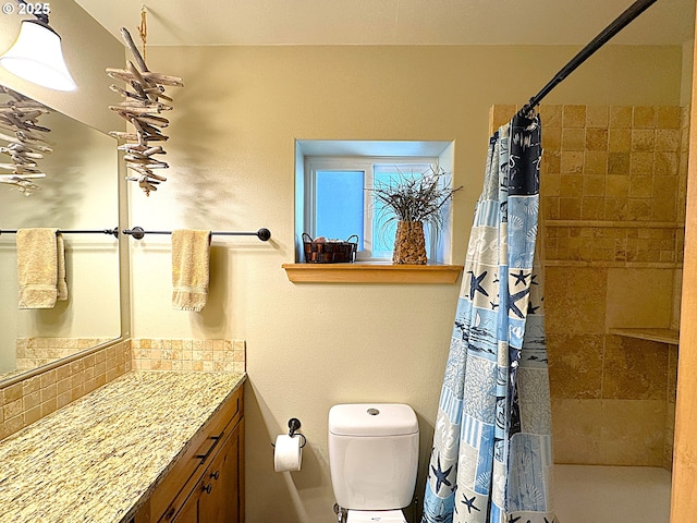 bathroom with toilet, vanity, and a tile shower