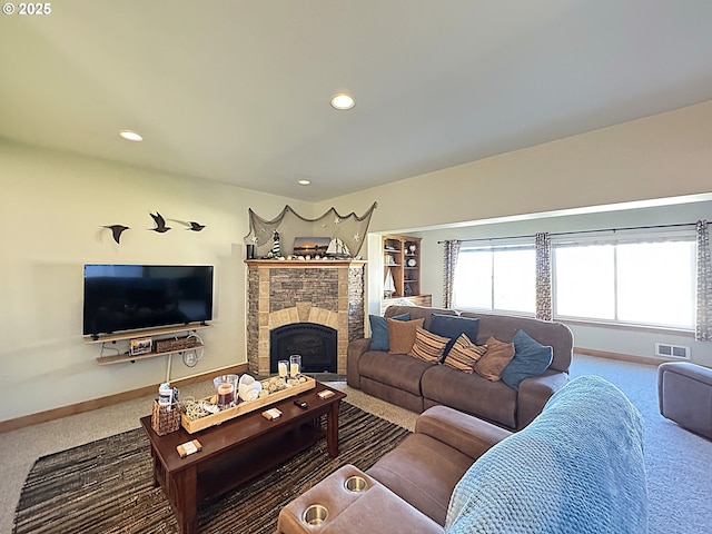 living room featuring visible vents, carpet flooring, a stone fireplace, and baseboards