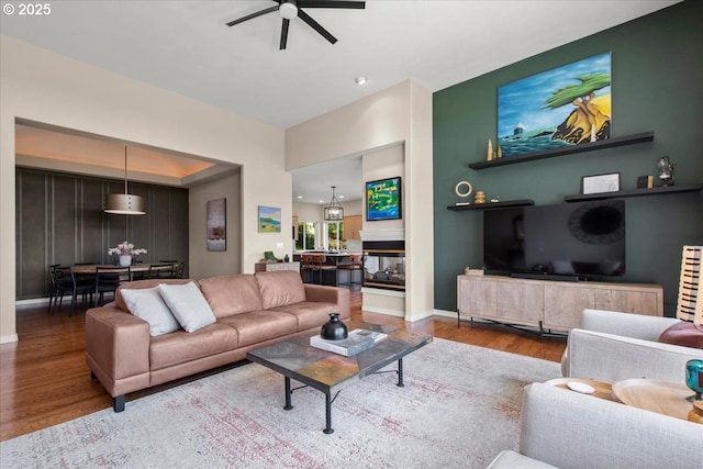living room with a ceiling fan, wood finished floors, and baseboards