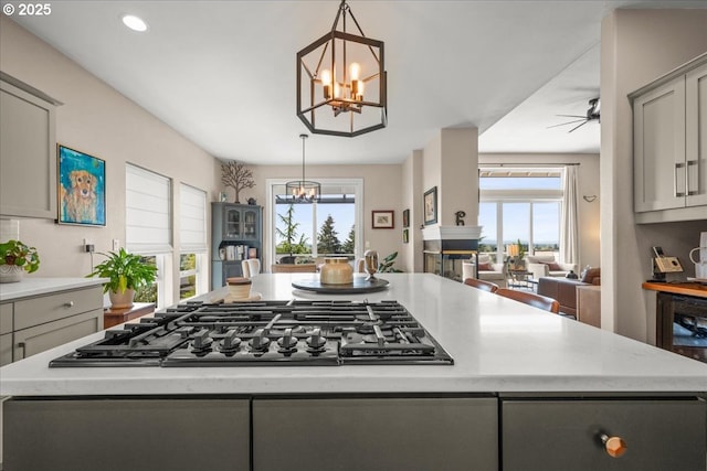 kitchen featuring gray cabinets, a healthy amount of sunlight, gas cooktop, and a kitchen island