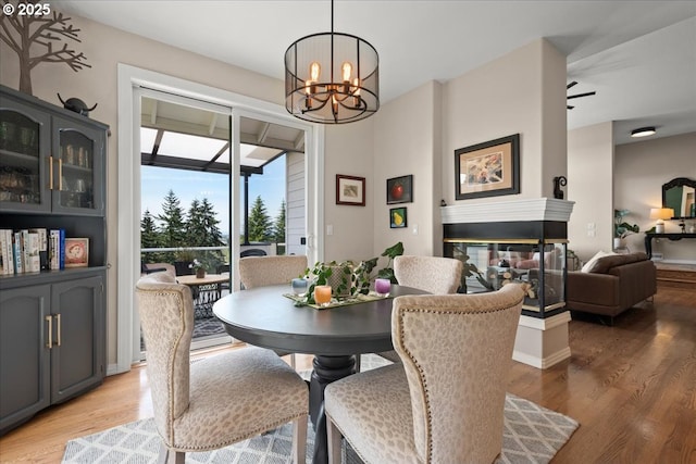 dining room featuring a chandelier, light wood-style flooring, and a multi sided fireplace