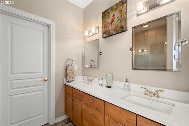 bathroom featuring double vanity, a tile shower, and a sink