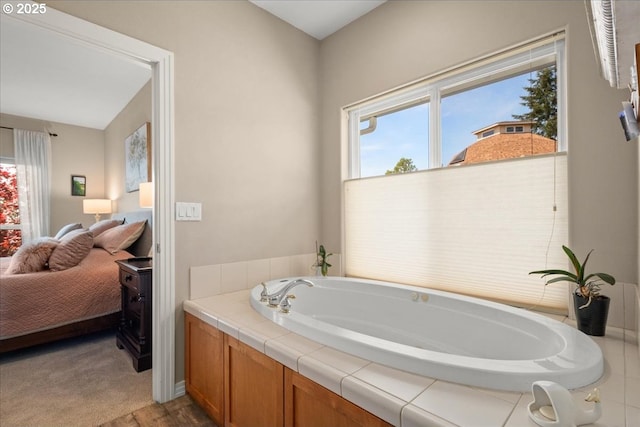 full bath featuring a wealth of natural light, ensuite bathroom, and a bath