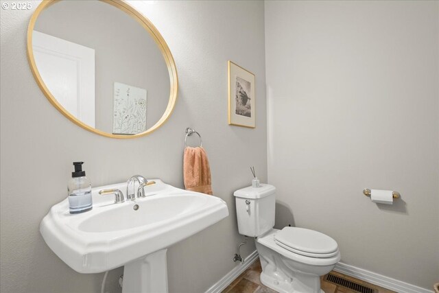 half bathroom featuring baseboards, visible vents, toilet, and a sink