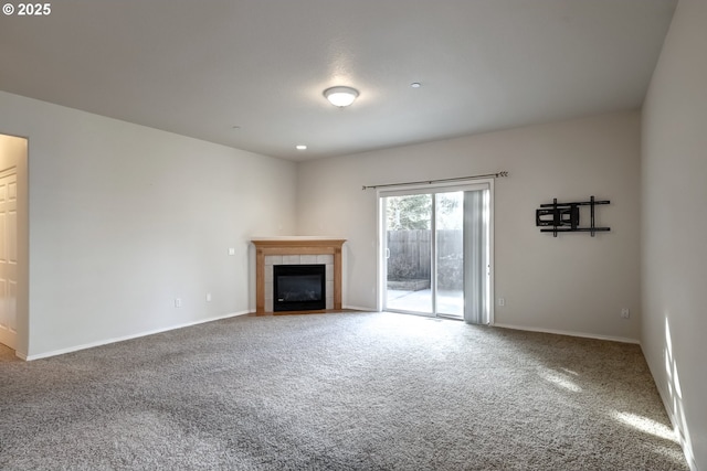 unfurnished living room with carpet, a tile fireplace, and baseboards