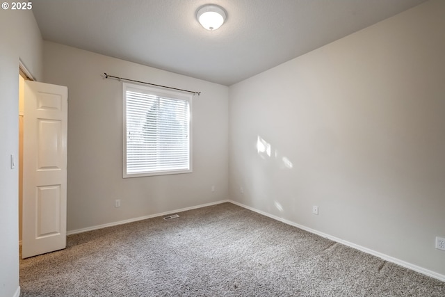 unfurnished room featuring carpet, visible vents, and baseboards