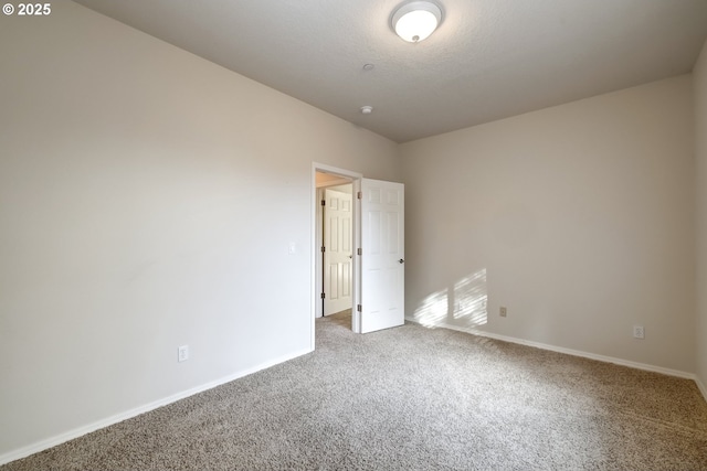 spare room featuring carpet floors, baseboards, and a textured ceiling