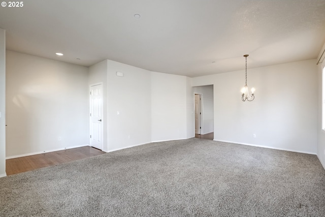 spare room with an inviting chandelier, baseboards, and dark carpet