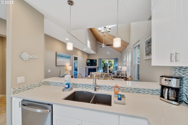 kitchen with vaulted ceiling, decorative light fixtures, white cabinetry, sink, and stainless steel dishwasher