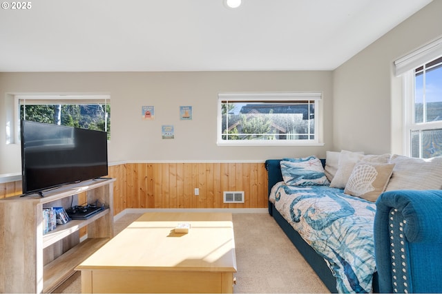 carpeted living room featuring wood walls