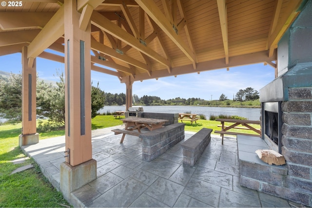 view of patio / terrace with area for grilling, a gazebo, an outdoor stone fireplace, and a water view