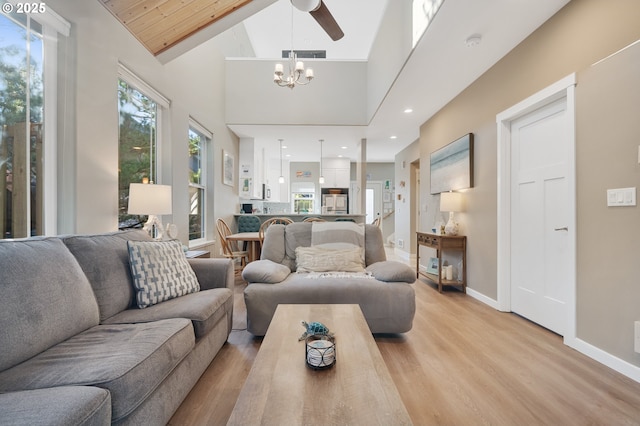 living room with an inviting chandelier, high vaulted ceiling, and light hardwood / wood-style flooring