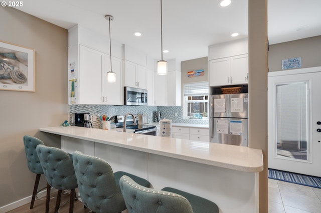 kitchen with stainless steel appliances, white cabinetry, pendant lighting, and kitchen peninsula