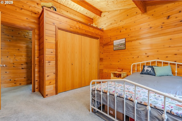 carpeted bedroom featuring beamed ceiling, a closet, and wood walls