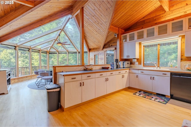 kitchen with sink, black dishwasher, beamed ceiling, light hardwood / wood-style floors, and white cabinets